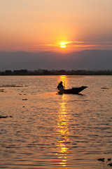 Fisherman silhouette at sunset in Inle Lake, Myanmar. Vertical s