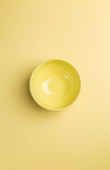 Yellow bowl on yellow background above view.Useful as a food bac