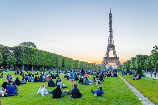 Fototapeta Eiffel Tower and people sitting on the grass watching sunset in Paris, France