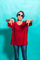 Hipster girl showing thumbs down. On a blue background.