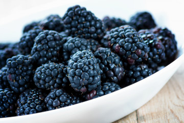 Fresh ripe blackberries in white bowl