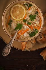 Chicken soup with pasta on a dark wooden background.
