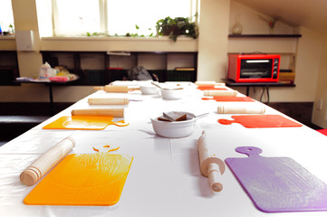 Multicolored cooking board on the table. Many Rolling Pin for the dough. Red microwave oven. Cooking class.