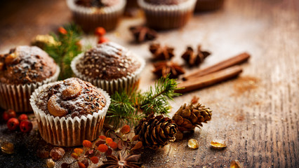 Fototapeta na wymiar Christmas chocolate walnut muffins among Christmas decoration on a wooden table