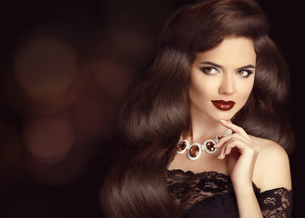 Fototapeta premium Elegant Brunette woman with long shiny wavy hair. Beauty makeup.