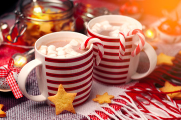 Christmas cups with hot chocolate and marshallow. Red plaid, ginger peonie in the form of stars, glowing lights. Vintage Christmas toys.