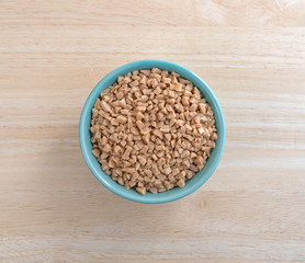 Toffee bits in a green bowl on a wood table top view.