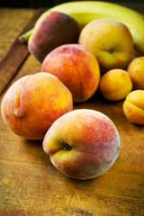 Fresh peaches, apricots and banana on a wooden table