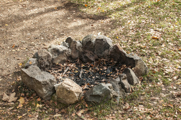 Manmade stone unlit open fireplace in nature in autumn