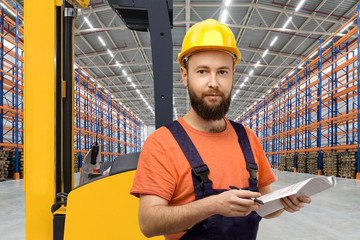 Young forklift driver in empty warehouse