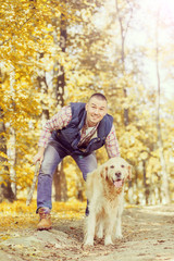 Young man walking a dog at the park in good weather. Boy and golden retriever.
Autumn environment