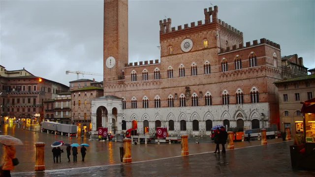 Campo Square with Mangia Tower, Siena, Italy at night. Illuminated landmark with colorful sunset sky