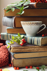 stack of old books, cup of tea and rowan berries. 