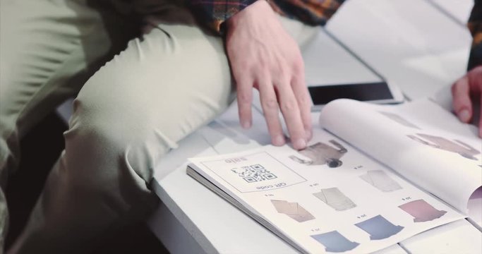 Man scanning qr code advertising with smartphone on clothes catalog modern technology and fashion shopping concept 