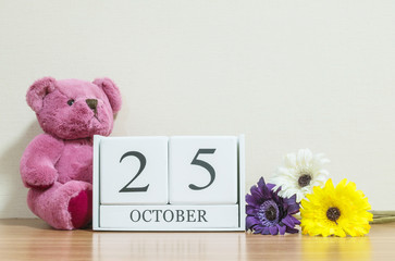 Closeup surface white wooden calendar with black 25 october word on brown wood desk and cream color...