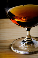 Bohemian glass of cognac on a wooden table