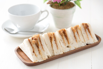 finger sandwiches triangles in wooden plate on white table