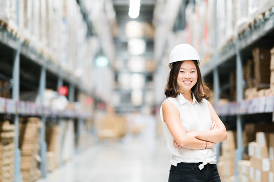 Beautiful young Asian engineer or technician smiling, warehouse