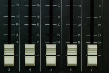 Audio mixer board close up on each channel controller.