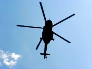 Silhouette military helicopter on a background of blue sky