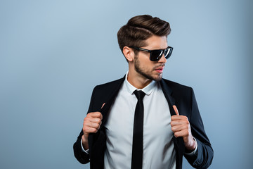 Portrait of handsome macho man in glasses touching his suit