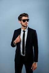 Young confident brutal businessman in black suit and spectacles