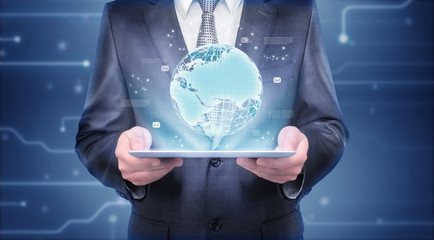 Businessman holding tablet which is showing hologram of the Earth