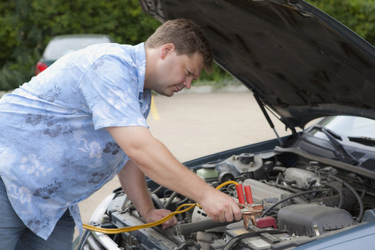 A Man Works Under The Open Hood Of A Vehicle; Edmonton, Alberta, Canada