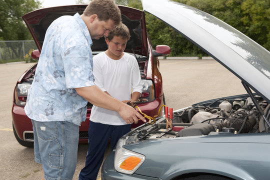 A Father And Son Work Together To Boost A Car Battery; Edmonton, Alberta, Canada