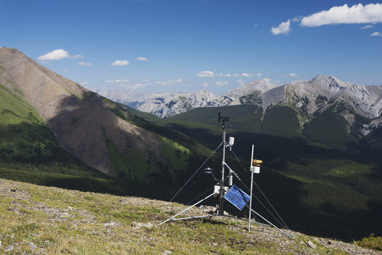 A Weather Station On Top Of A Ridge With Mountains And Valley In The Distance And Blue Sky With Clouds; Alberta, Canada