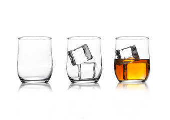 Glasses with whiskey and ice cubes and empty glass