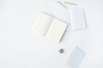 clean blank sketchbook, pencils and pencil sharpener on white background. flat lay, top view