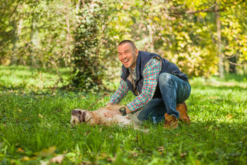 Young man walking a dog at the park in good weather. Boy and golden retriever.
Autumn environment