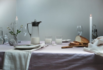 elegant table setting. tablecloth, milk in the old Countess, bread, flowers in a vase, candle