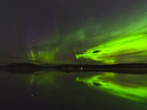 Beautiful aurora borealis over the lake with water reflection. Natural background.