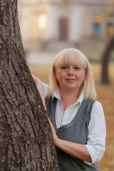 Senior business woman walking in the autumn Park. A woman in a classic clothing style. Elegant woman in a costume. Business lady.