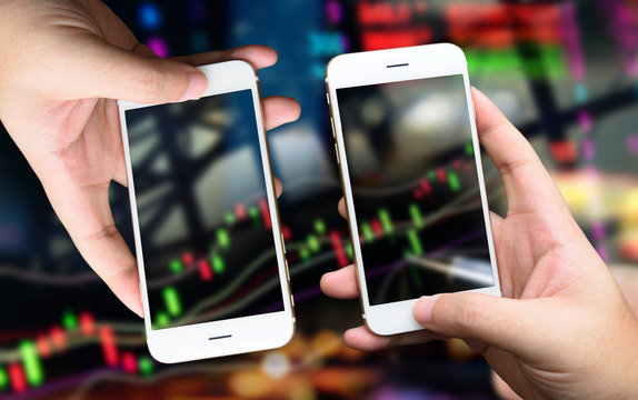 Fintech concept image. Hand holding two smart phones buy and sell stock on mobile screen. stock market concept image background