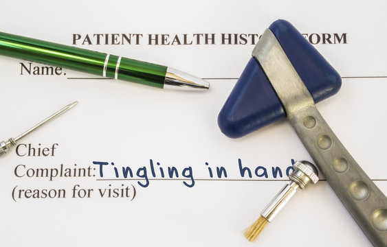 Complaint tingling in hands. Patient health history is on table of neurologist, which contains complaint tingling in hands surrounded by neurological hammer, tools to determine sensitivity of skin