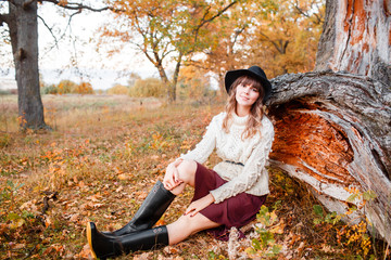 beautiful girl in the autumn forest. young with long hair. Dressed in a sweater and hat