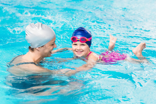 Smiling little girl, learning swimming with instructor
