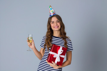 Woman in celebration cap holding a present and a glass