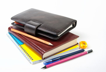 Diary, notebook, pen, pencils and pencil sharpener on a white background