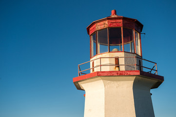 Fototapeta na wymiar Top of a red and white old lighthouse over blue sky in Gaspesie,