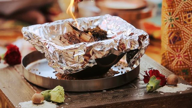 Wood burns in the bowl on table during pre-wedding Hindu ceremony