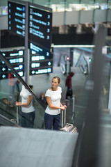 Young female passenger at the airport, using her tablet computer