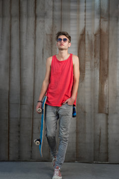 cool street skateboarder with sunglasses in front of iron wall.
