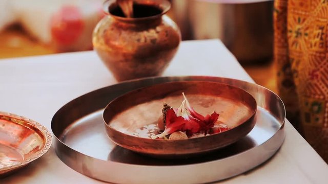 Hindu woman puts red petals on bronze plate