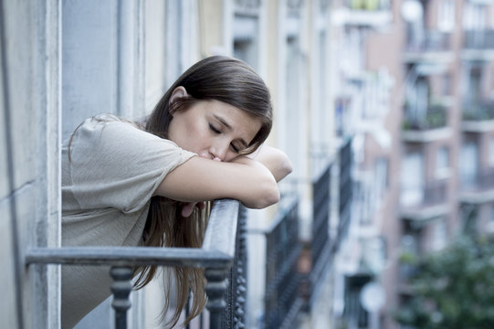 young sad beautiful woman suffering depression looking worried and wasted on home balcony