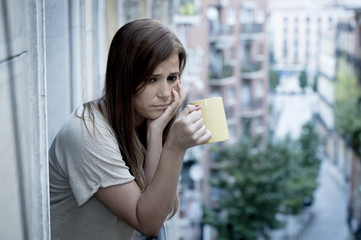 young sad beautiful woman suffering depression looking worried and wasted on home balcony
