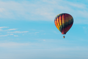 This is a photo of a beautiful hot air balloon slowly sailing through a calm blue sky.